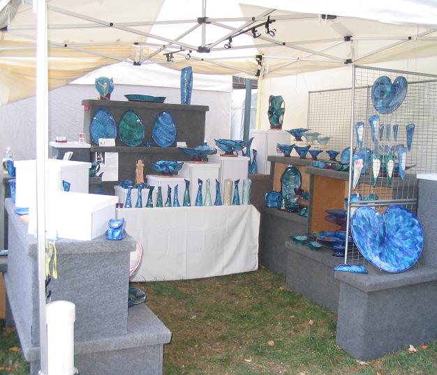 An artist booth displaying framed artwork and colorful pieces at the St. James art fair.
